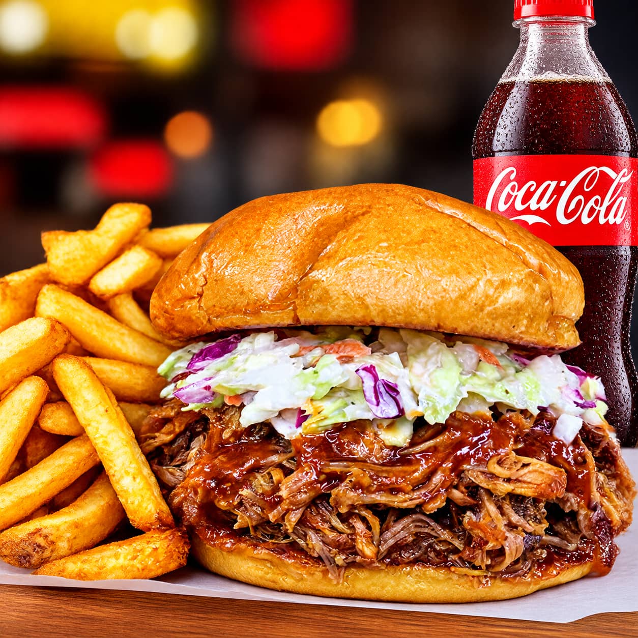 Primer plano de sándwich de cerdo desmechado en salsa BBQ con coleslaw en pan brioche